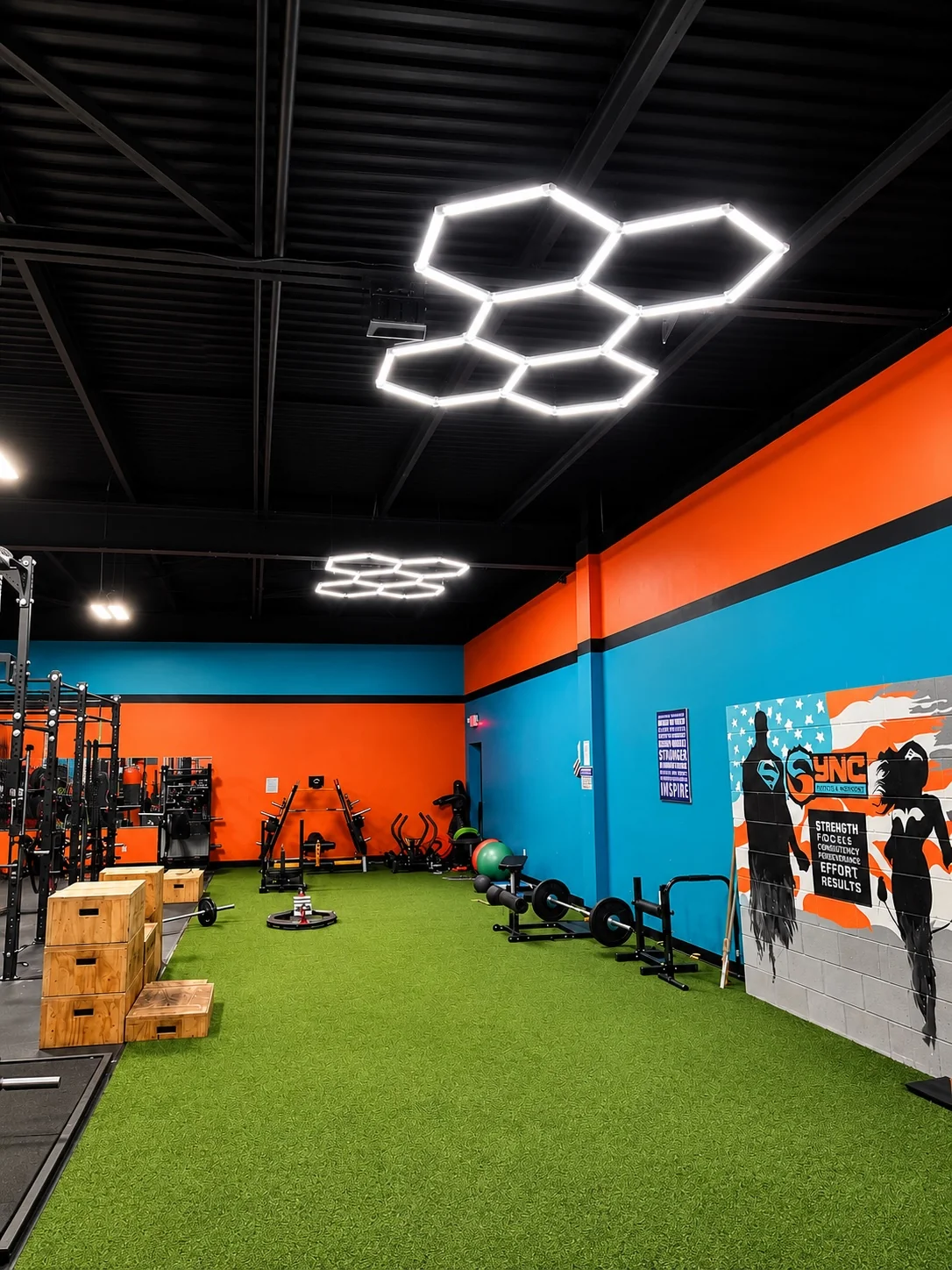 The open turf training area at Sync, with orange and teal walls and hexagonal ceiling lights