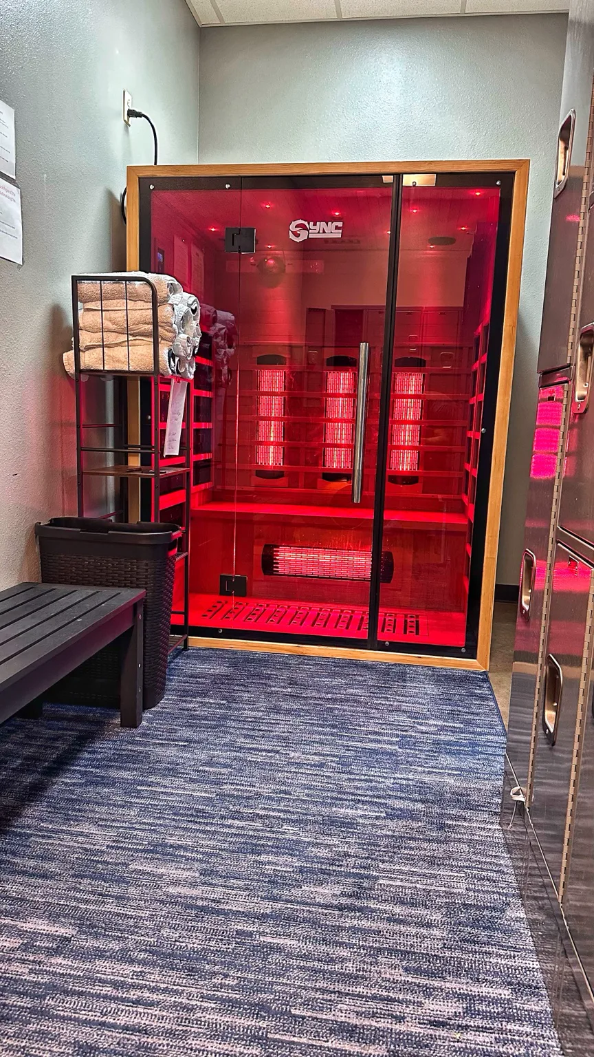 Sync’s wood-and-glass red-light sauna with its red lights illuminated
